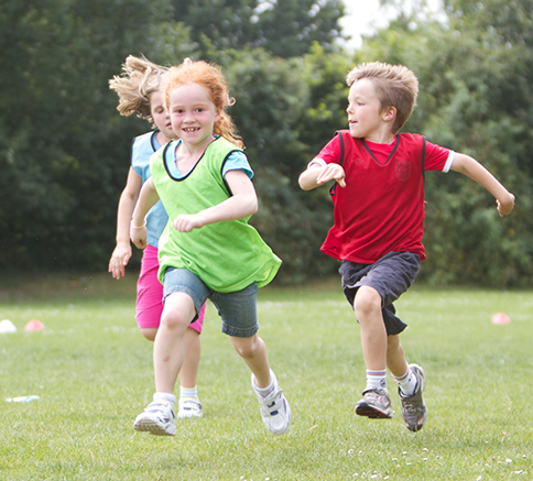 Children racing across the grass at a holiday camp