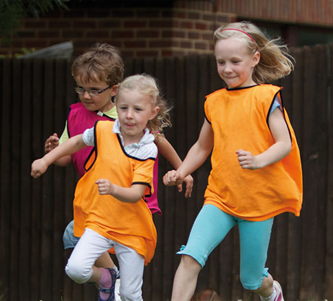 Children in orange bibs running at an after school club